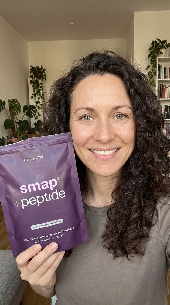 Creatorin mit Locken hält smap +peptide in die Kamera